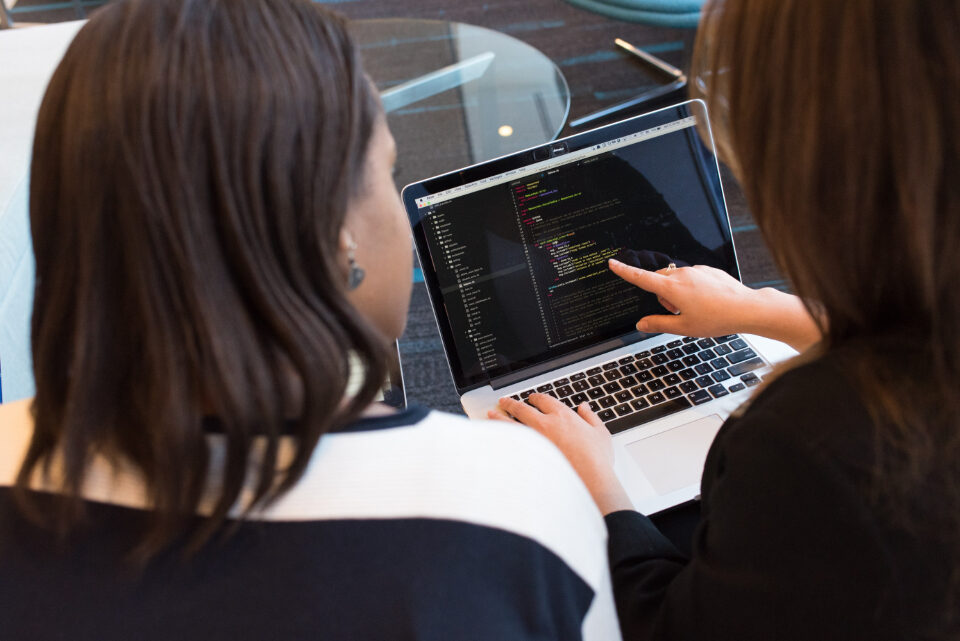 Two people looking at code together on a laptop