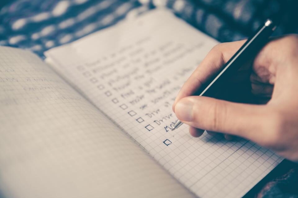 A hand ticking items off a handwritten checklist