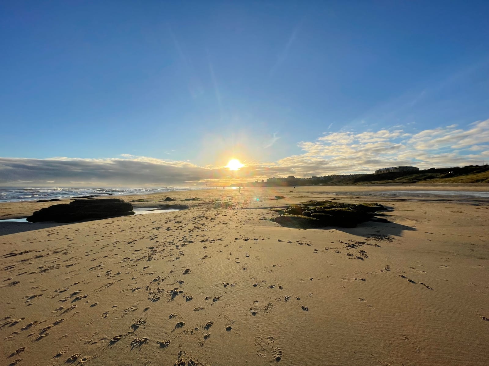 Tynemouth Longsands at low tide, the sun low over the sea